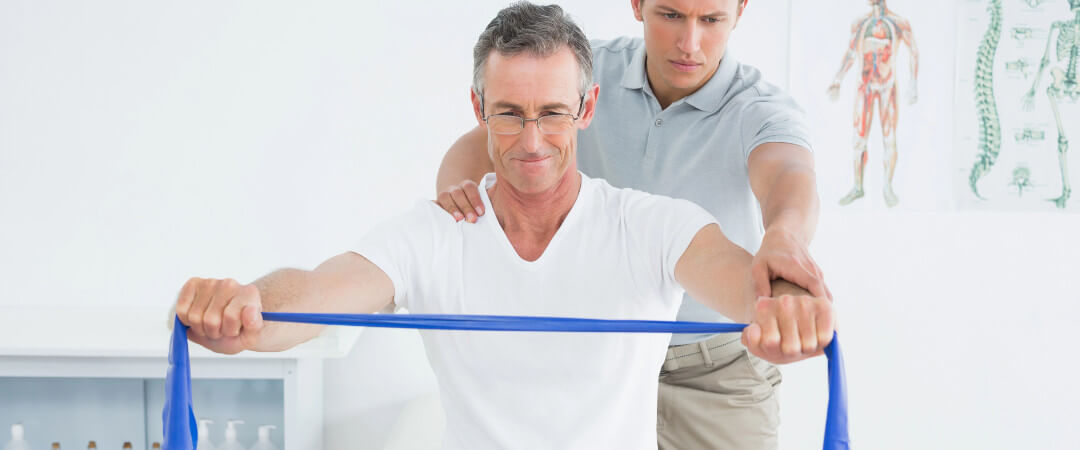 Therapist massaging mans shoulder in gym hospital